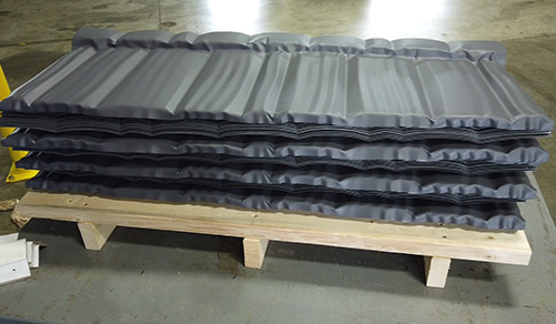 Dark grey metal roofing materials on a sitting on a wooden pallet.